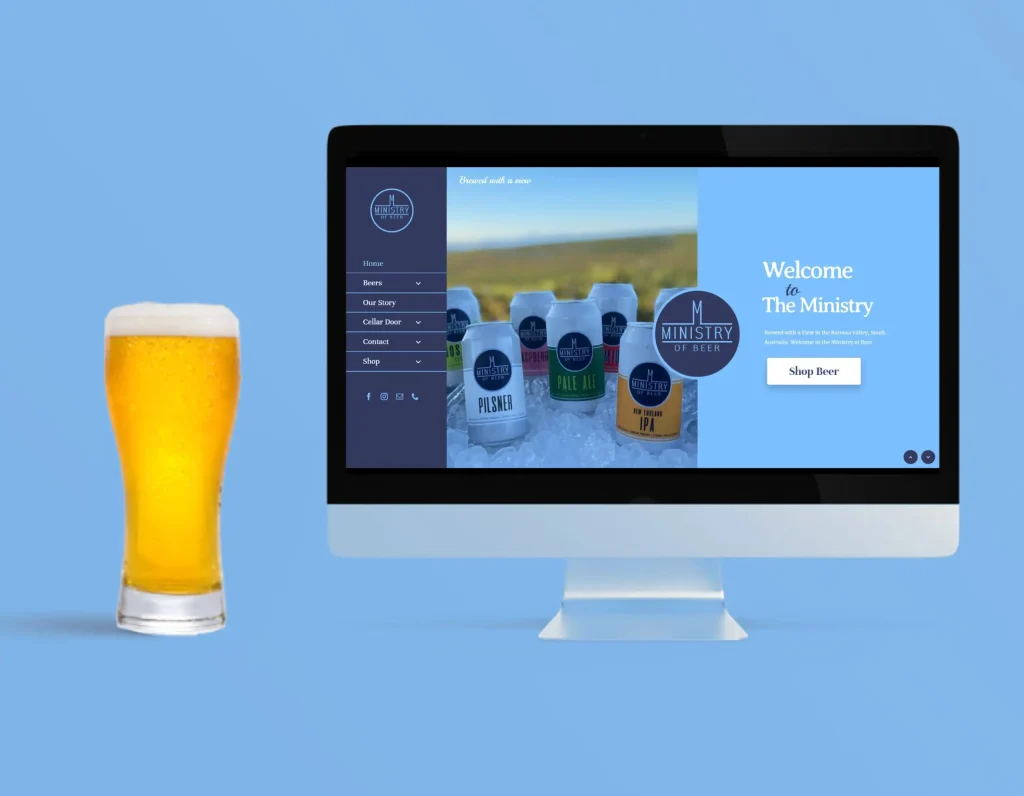 Computer screen showing the Ministry of Beer website with beer cans on ice, displayed beside a tall glass of beer on a blue background.